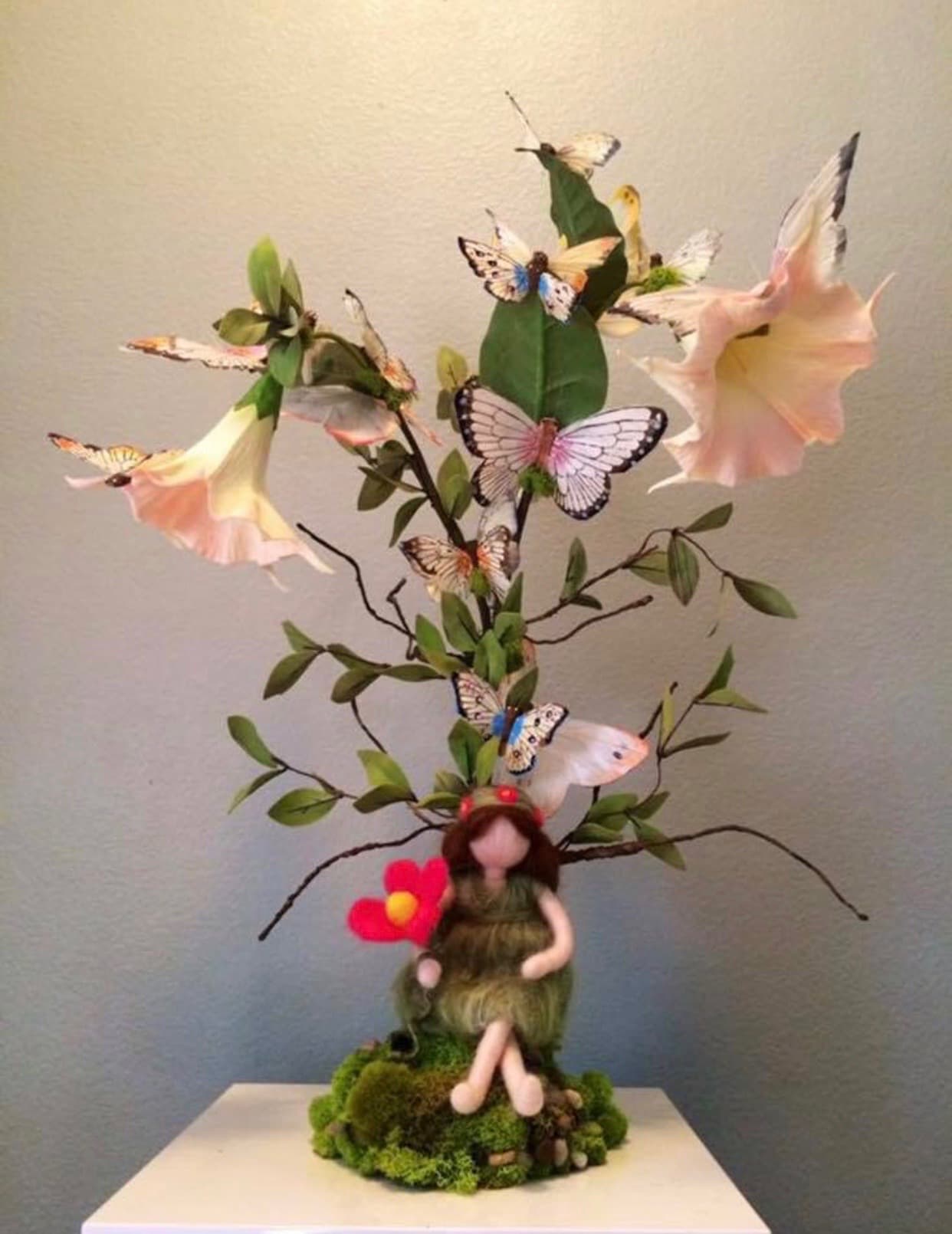 Whimsical handcrafted fairy beneath flowering branches filled with delicate butterflies